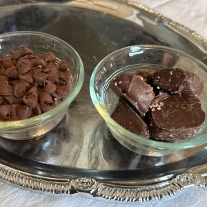 Photo of chocolate chips and caramel, each in their ramekins, sitting on a silver tray to showcase ingredients used in the brownie recipe.